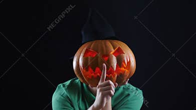 Halloween. Pumpkin head showing gesture of silence.