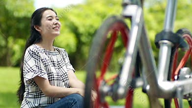 Asian woman sitting and resting after cycling outdoors