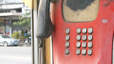 Old shabby red telephone set on a city street. Vintage telephone in the phone booth