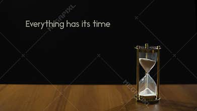 Everything has its time, wise phrase about patience, sand flowing in hourglass