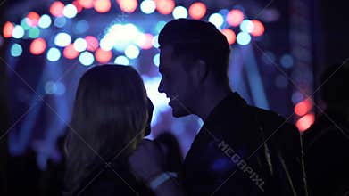 Smiling couple dancing and talking at concert, people enjoying music at club