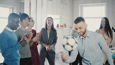 Happy Caucasian worker juggling football on head. Cheerful mixed race executives celebrate business success in office 4K