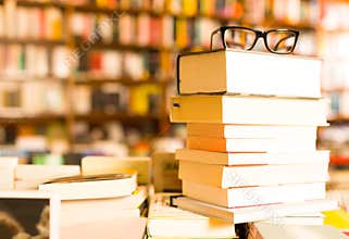 Glasses on top of stack of books lying on table in bookstore