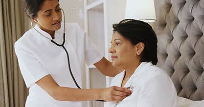 Female doctor examining mature woman with stethoscope in bedroom 4k