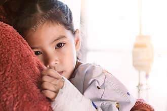 Sick asian child girl who have IV solution hugging her mother