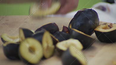 Chef cuts ripe plums with knife.