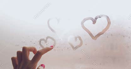 Hand Drawing Hearts With Fingers On Steamed Window In A Rainy Day Closeup
