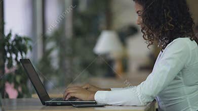 Biracial lady typing email on laptop at office, using computer for communication