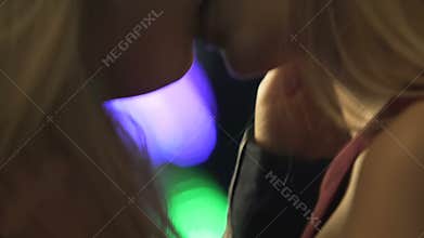Gay female couple making out in nightclub, with their breasts touching gently