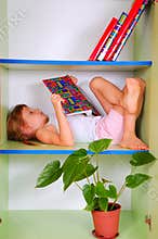 Child reading a book in a bookcase