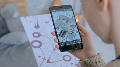 Woman using smartphone with augmented reality app and placing furniture in room