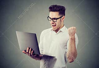 Excited man with laptop computer celebrating success