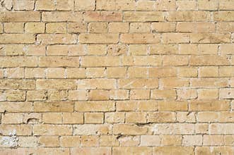 Textured background of a stone brick of yellow antediluvian masonry. Partially destroyed wall. Brick grunge background