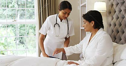 Female doctor measuring blood pressure of mature woman in bedroom 4k