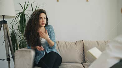 Upset young woman talking about her problems with professional female psychoanalyst in psychotherapist office indoors