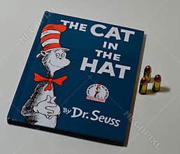 The well known book The Cat in the Hat is on a plain white desk next to three bullets