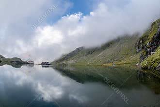 Balea lake and Balea Hotel in spring time with clouds