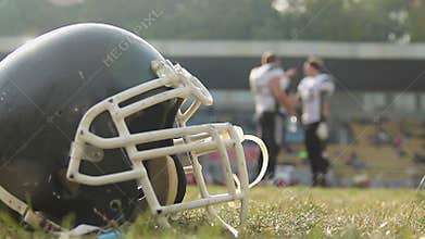 American football players having break on field, drinking water, communicating