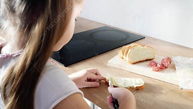 Little child making sandwich with butter and sausage