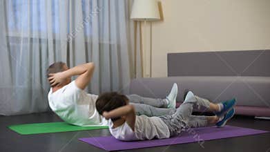 Father with son doing abdominal crunches at home, showing benefit of sports