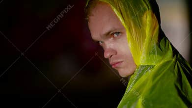 Person in cloak holding red balloon turns and looks into the camera
