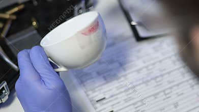 Criminal specialist taking lipstick print from white cup from murder scene