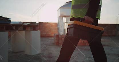 Closeup expert builder coming to his work desk putting his instrument bag on desk , he is wearing safety vest. slow