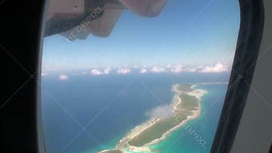 View from window of airplane on ocean coast.