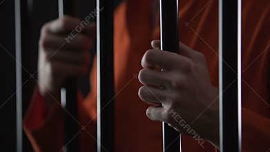Hands of angry arrested male gripping prison bars, unfair judgment, closeup