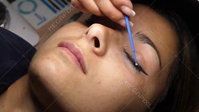 Beauty and fashion concept. Preparation for Eyelash Extension Procedure. Beautician prepares the eyelashes of a young