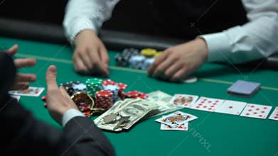 Sad casino player losing poker game, professional croupier taking all chips