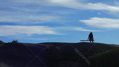 Girl sitting alone on bench with sky