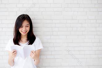 Beautiful portrait young asian woman happy open the book with cement or concrete background