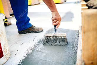 Construction worker using brush and primer for hydroisolating and waterproofing house