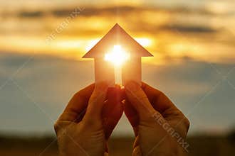 Hands with paper prayer house in the hands .