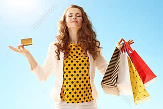 Happy young woman with shopping bags and credit card doing yoga