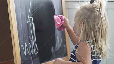 The baby in the striped dress is erasing the picture from the board