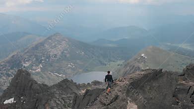 Aerial shot of silhouette of a man climbing to the top of the mountain.