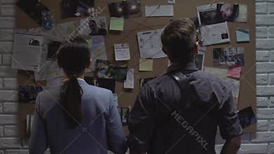 Secret agency teammates searching for criminal movements on investigation board