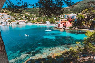 Assos village, Kefalonia, Greece. View on tourquise transparent water framed between green pine grove branches. Deep