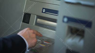 Man in suit finishing banking transaction, pressing cancel to remove card