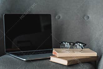 Laptop with empty screen and books lying