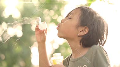 Lovely Asian little girl blowing soap bubble