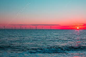 Crimson dawn. Clean energy offshore wind farm turbines at sunrise