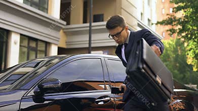 Businessman receiving good news and dancing, talking on phone near luxury car