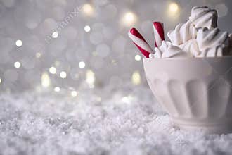Hot Coffee cup with marshmallows and red candy cane on a frosty winter background. Christmas holidays background.