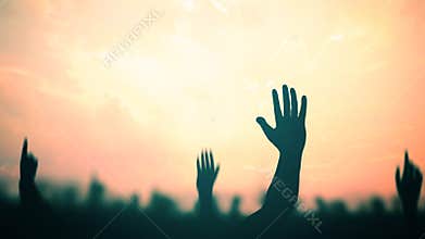 Silhouetted Hands Raised in Celebration against Hazy Orange Sunset Sky