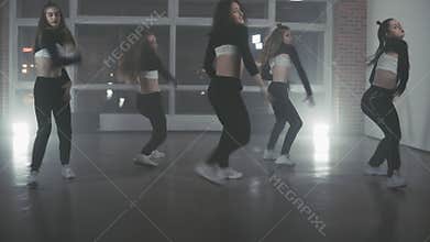 Girls enjoying hip hop moves in dark studio. Group of young hip-hop dancers