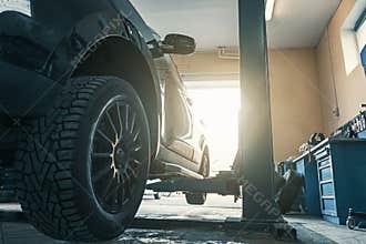 Car in garage of auto repair service shop with special repairing equipment, changing tires