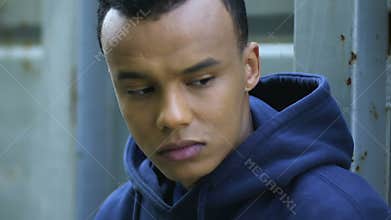 Upset afro-american teenage immigrant hiding, wearing hoodie, social rejection